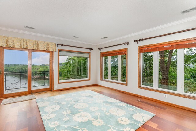 unfurnished sunroom with visible vents, ornamental molding, and wood finished floors