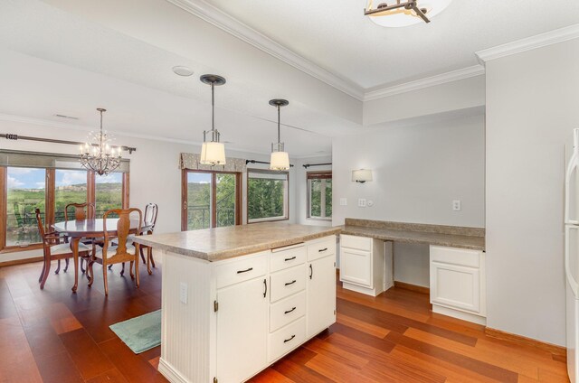 kitchen with hanging light fixtures, dark wood-type flooring, white cabinets, and a wealth of natural light