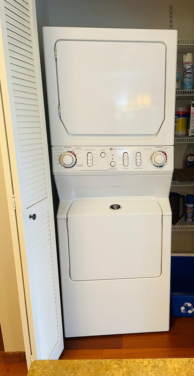 washroom with wood finished floors, laundry area, and stacked washer / dryer