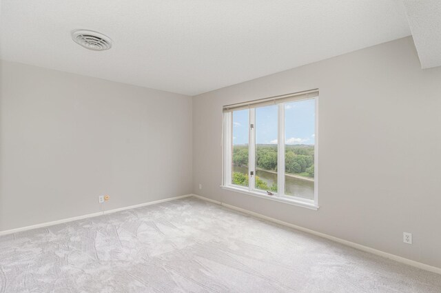 carpeted empty room featuring baseboards, visible vents, and a textured ceiling
