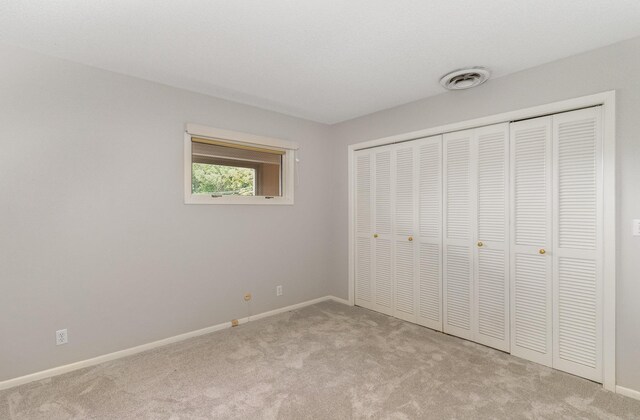 unfurnished bedroom with a closet, carpet flooring, baseboards, and visible vents
