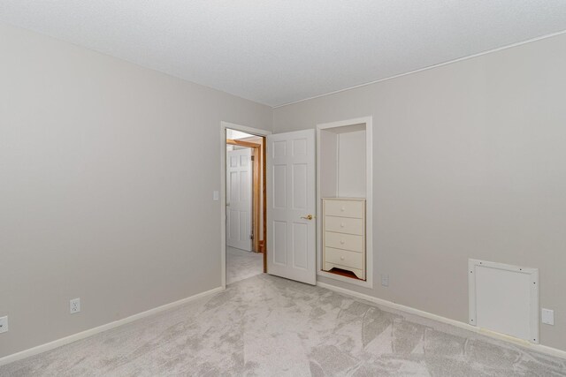 carpeted empty room with baseboards and a textured ceiling