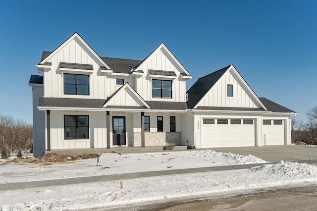 modern inspired farmhouse with board and batten siding, roof with shingles, covered porch, driveway, and an attached garage