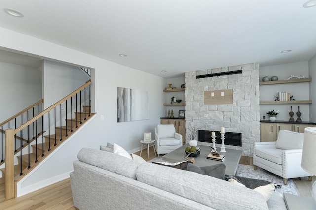 living room with light wood finished floors, stairs, a fireplace, and baseboards