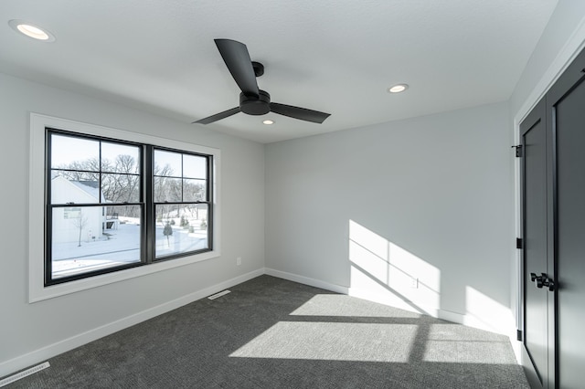 unfurnished room with baseboards, visible vents, dark carpet, and recessed lighting