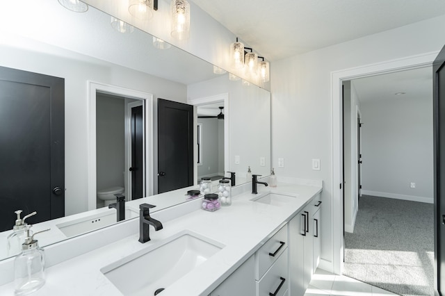 bathroom with double vanity, toilet, and a sink