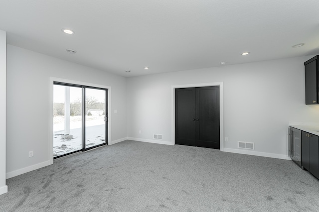 unfurnished living room featuring recessed lighting, carpet flooring, visible vents, and baseboards