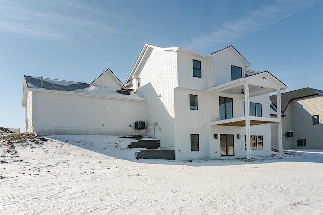 snow covered house featuring cooling unit and a balcony