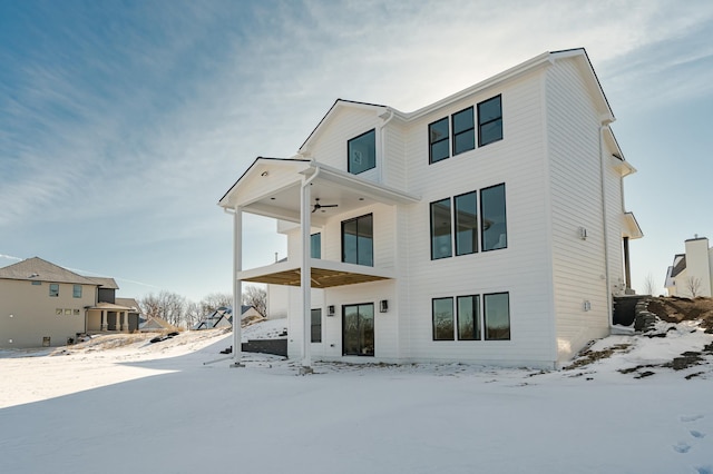 snow covered rear of property featuring a ceiling fan