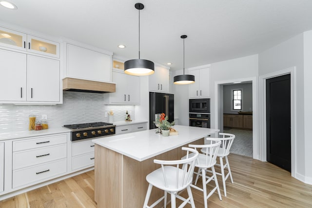 kitchen featuring a kitchen bar, black appliances, light wood-style floors, and a center island