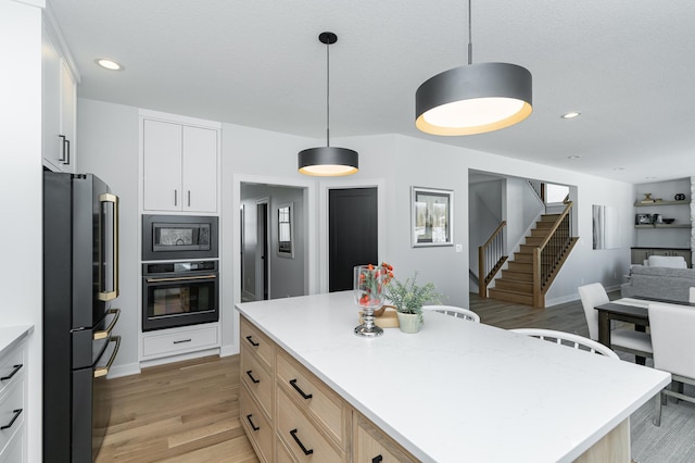 kitchen featuring open floor plan, recessed lighting, black appliances, and light wood-style floors