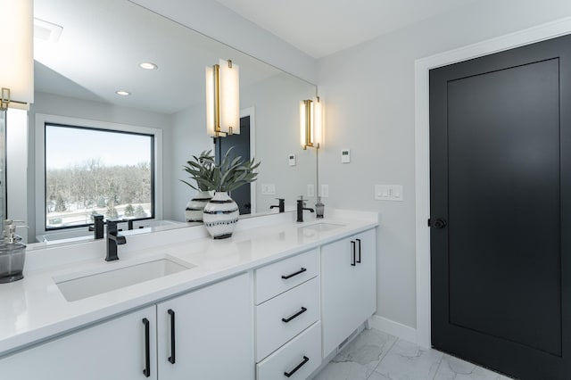 full bath featuring double vanity, recessed lighting, marble finish floor, and a sink
