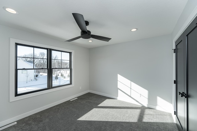 spare room featuring visible vents, recessed lighting, baseboards, and dark carpet