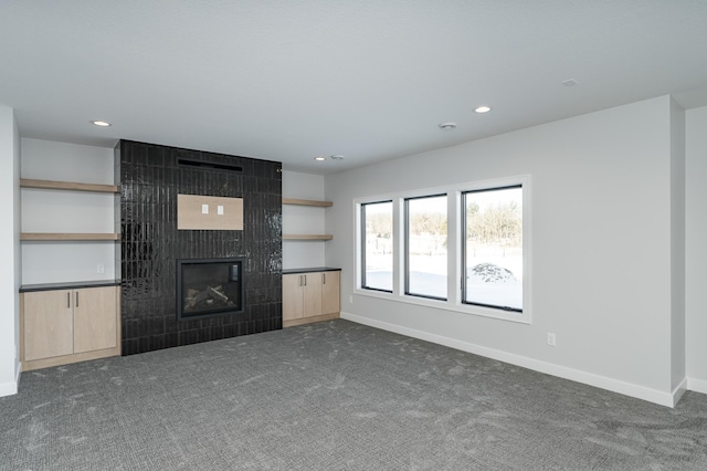 unfurnished living room with recessed lighting, a fireplace, baseboards, and dark carpet