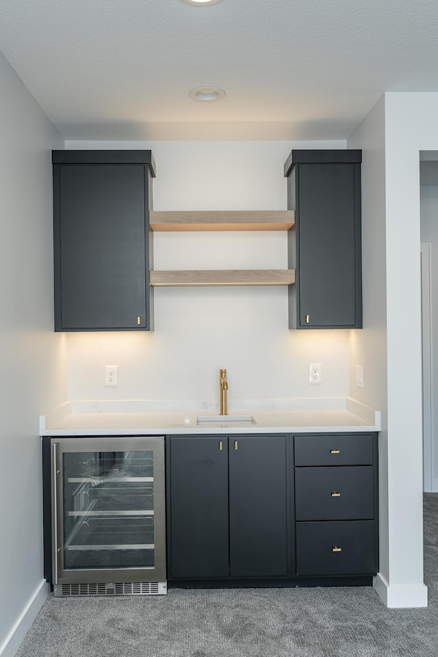 bar featuring a sink, baseboards, wine cooler, and carpet flooring