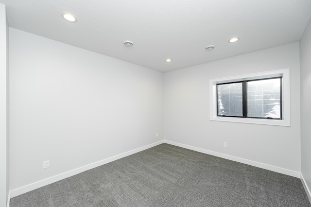 spare room featuring recessed lighting, baseboards, and dark colored carpet
