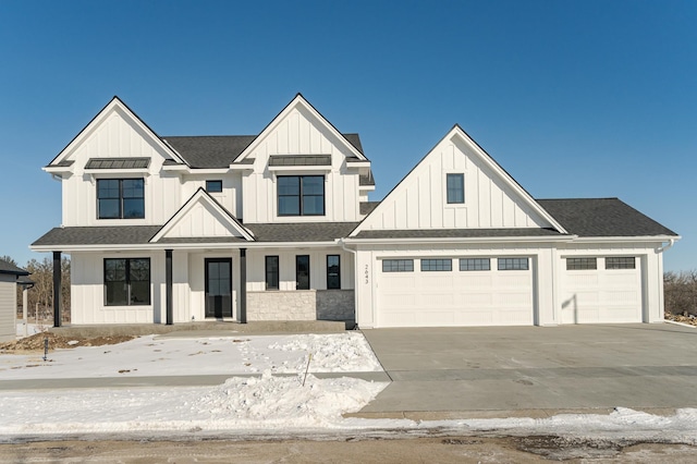 modern farmhouse featuring concrete driveway, an attached garage, board and batten siding, and a shingled roof
