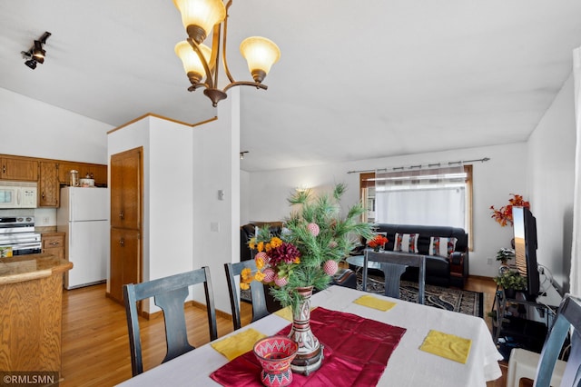 dining space featuring lofted ceiling, an inviting chandelier, and light hardwood / wood-style floors