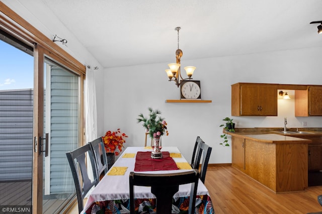 dining room with light wood-type flooring, lofted ceiling, a chandelier, and sink