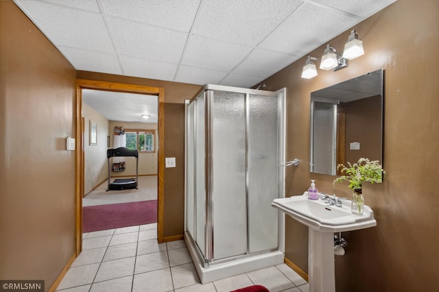 bathroom featuring a paneled ceiling, a shower with door, and tile patterned floors