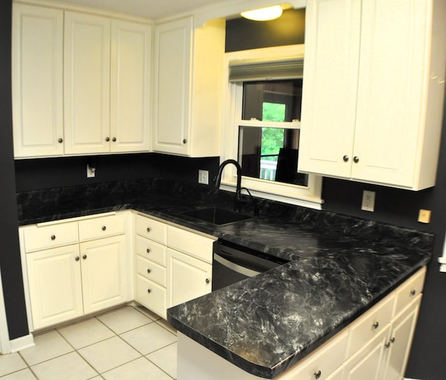 kitchen featuring dark stone counters, white cabinets, light tile patterned floors, sink, and black dishwasher