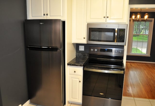 kitchen featuring white cabinets, stainless steel appliances, and an inviting chandelier