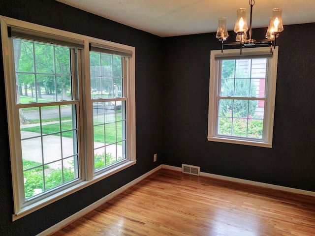 spare room featuring light wood-type flooring and a chandelier