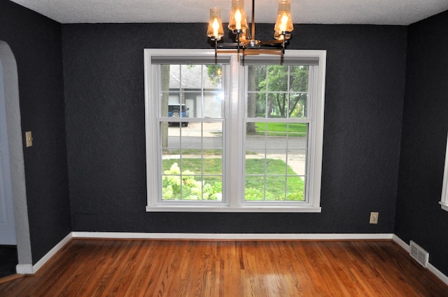 unfurnished dining area featuring wood-type flooring and a notable chandelier