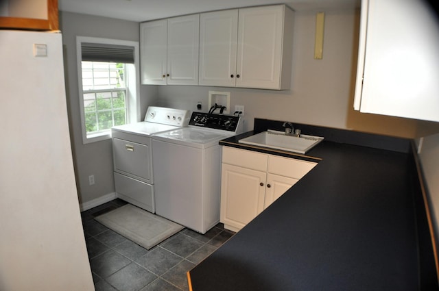 clothes washing area featuring dark tile patterned flooring, cabinets, washer and clothes dryer, and sink