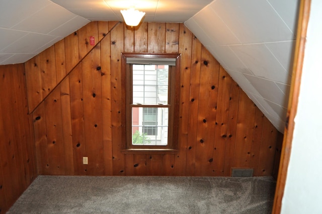 additional living space featuring carpet flooring, vaulted ceiling, and wooden walls