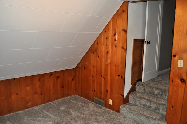 additional living space with carpet floors, lofted ceiling, and wood walls