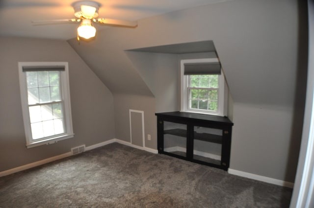 additional living space with ceiling fan, dark colored carpet, and vaulted ceiling