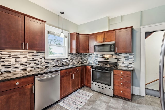 kitchen with appliances with stainless steel finishes, backsplash, pendant lighting, light tile patterned floors, and dark stone countertops