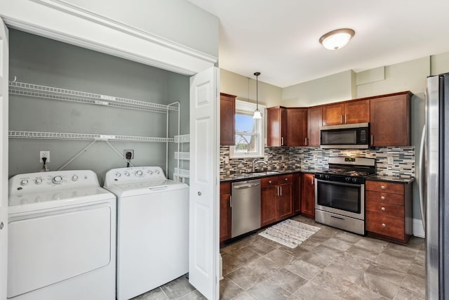 kitchen featuring appliances with stainless steel finishes, tasteful backsplash, light tile patterned floors, independent washer and dryer, and hanging light fixtures