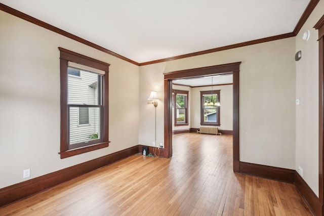 spare room featuring light hardwood / wood-style flooring, radiator, and ornamental molding