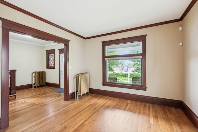 unfurnished room with light wood-type flooring, crown molding, and radiator heating unit