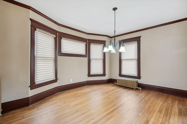 empty room featuring an inviting chandelier, light hardwood / wood-style flooring, ornamental molding, and radiator