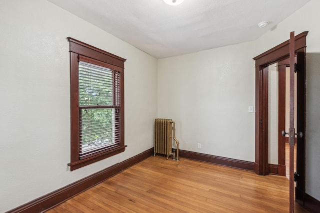 unfurnished room with radiator heating unit and light wood-type flooring