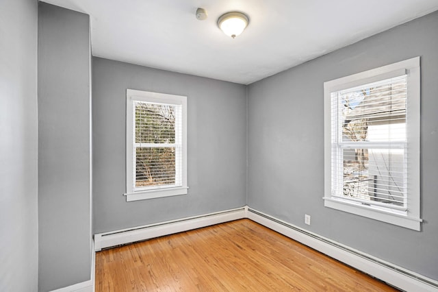 unfurnished room featuring hardwood / wood-style flooring, plenty of natural light, and a baseboard radiator