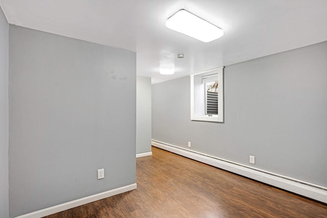 empty room featuring hardwood / wood-style floors and a baseboard heating unit