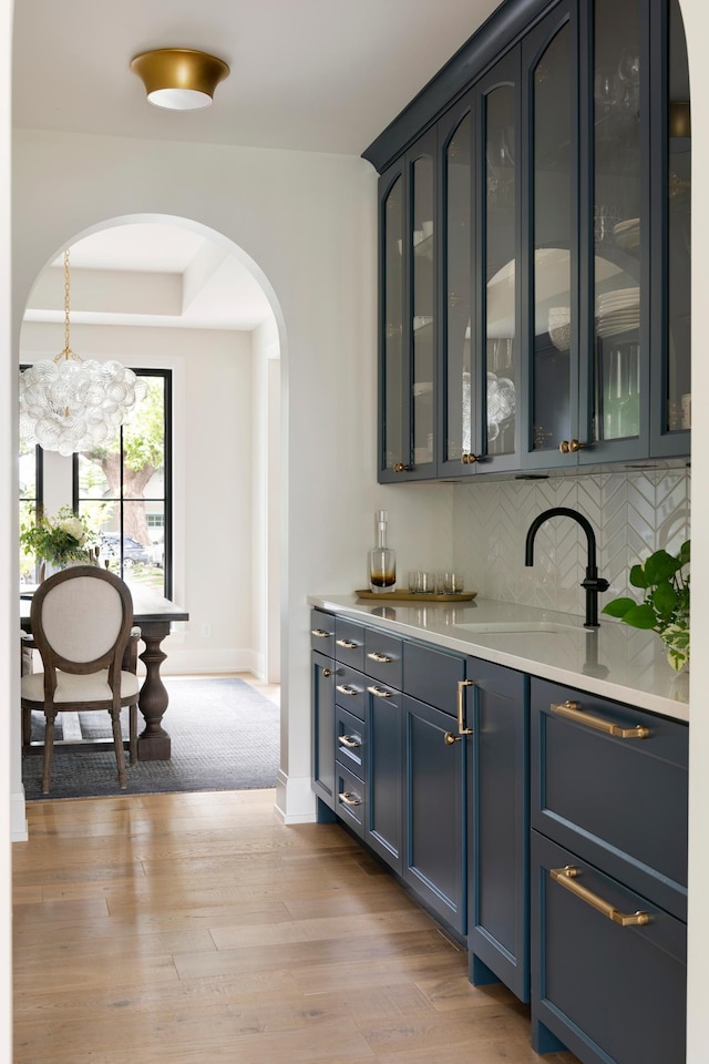 bar with backsplash, sink, light colored carpet, a notable chandelier, and blue cabinets