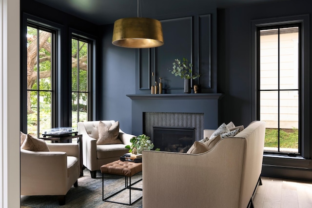 living room with hardwood / wood-style flooring, a tiled fireplace, and a healthy amount of sunlight