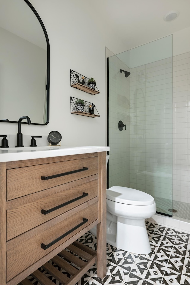 bathroom featuring tile patterned flooring, toilet, vanity, and a shower with shower door