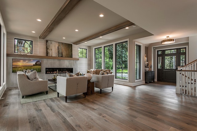 living room featuring beam ceiling, a large fireplace, and hardwood / wood-style flooring