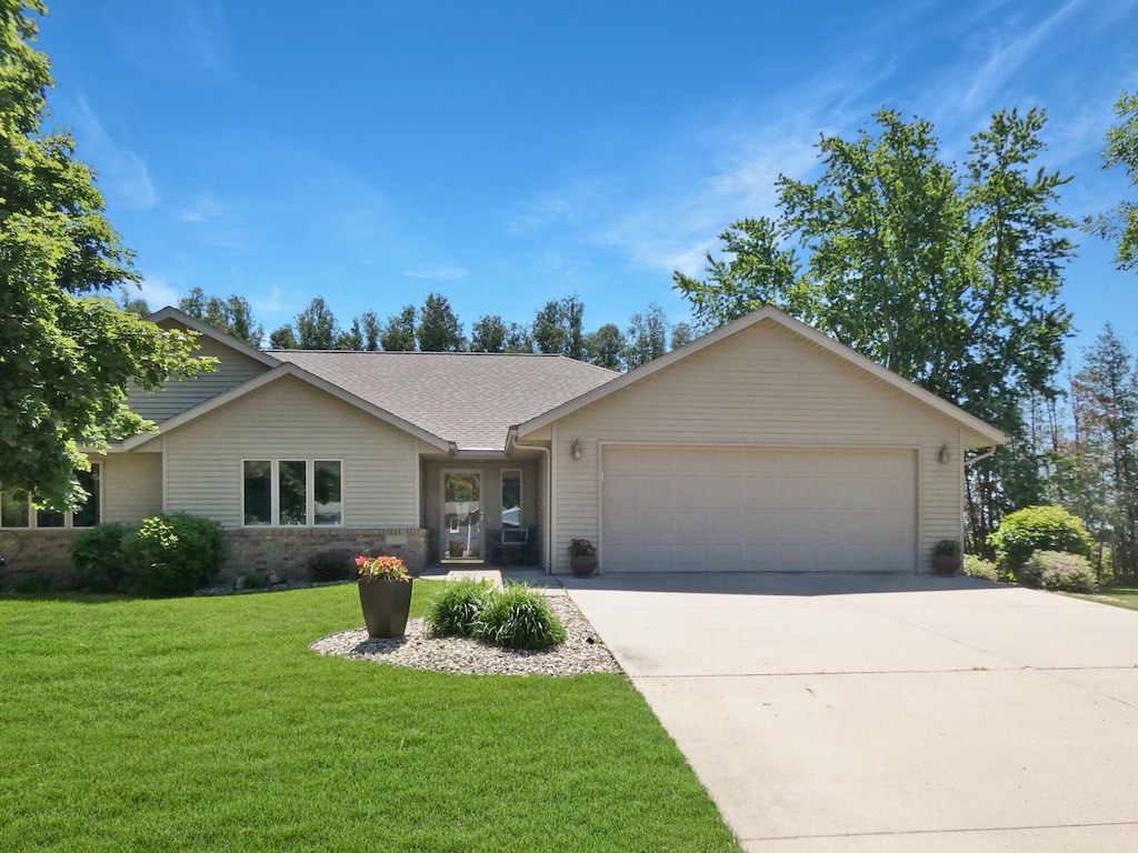 ranch-style house with a garage, driveway, a front lawn, and a shingled roof