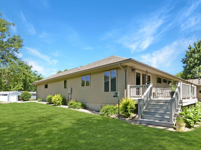 rear view of property featuring a wooden deck and a lawn