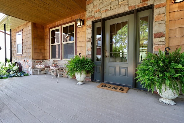 view of exterior entry featuring stone siding and covered porch