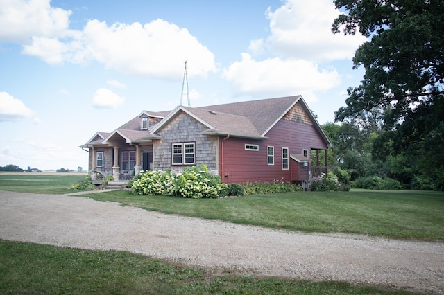 view of front of property featuring stone siding, a front lawn, roof with shingles, and a porch