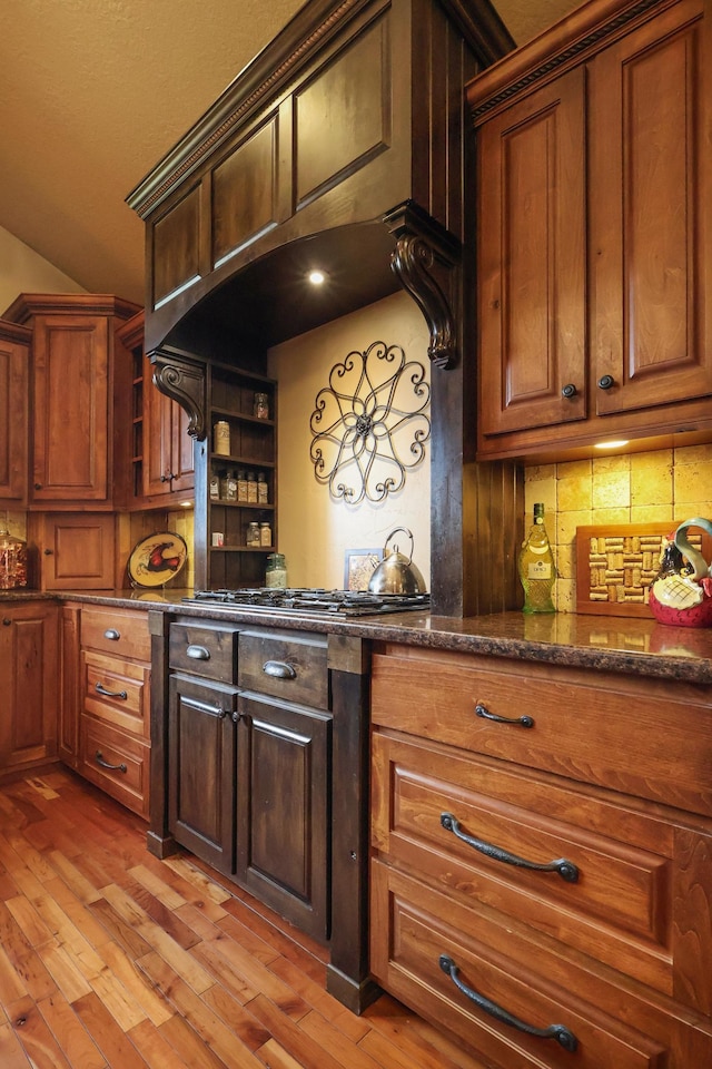 kitchen with dark stone counters, open shelves, tasteful backsplash, and light wood-style flooring