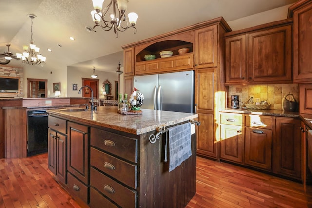 kitchen with pendant lighting, black dishwasher, a kitchen island with sink, a sink, and stainless steel fridge